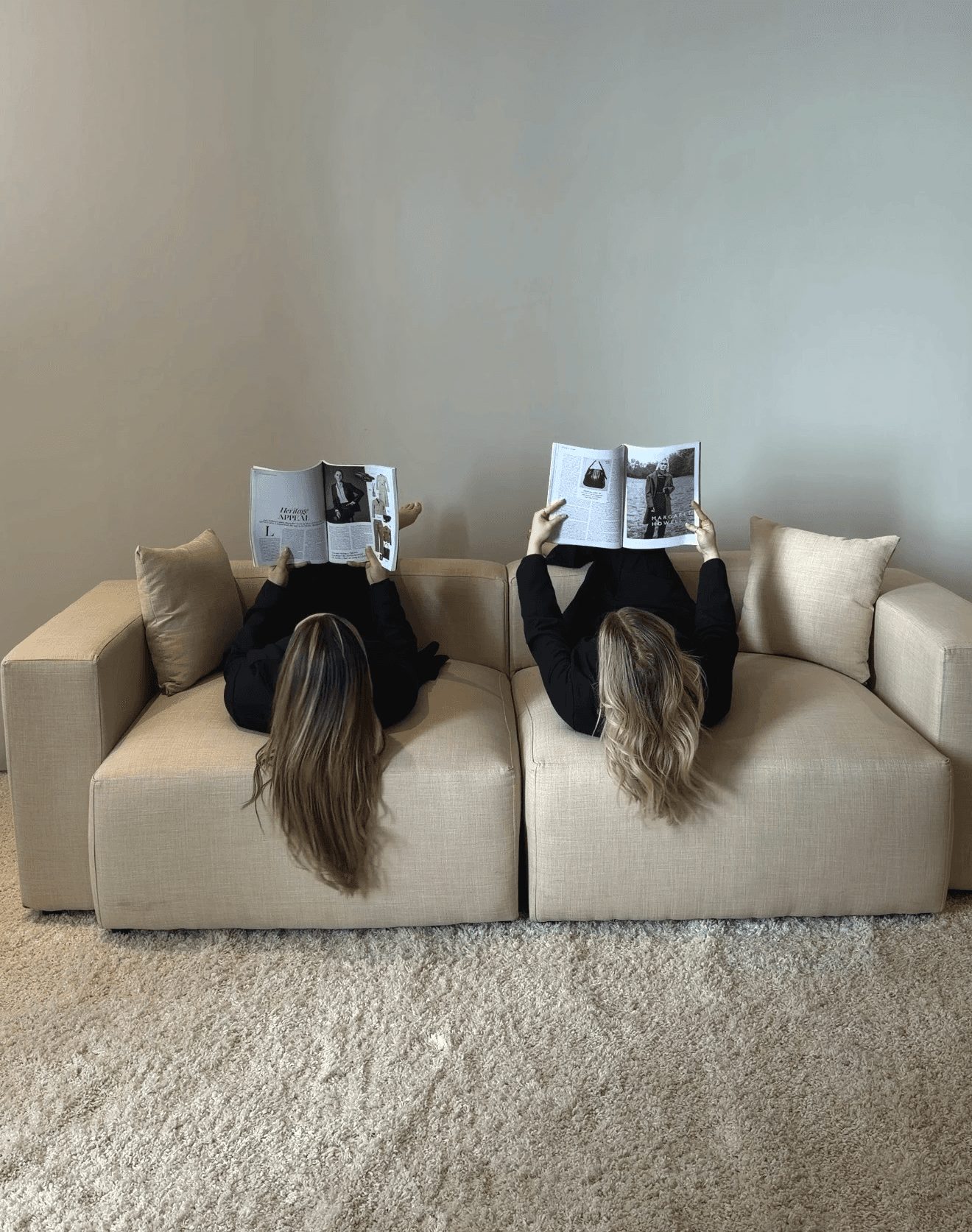 Two members of the ROHA team lying back on a sofa, each reading a magazine